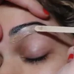 Eyebrow waxing course preview: applying wax along the brow with a wooden stick